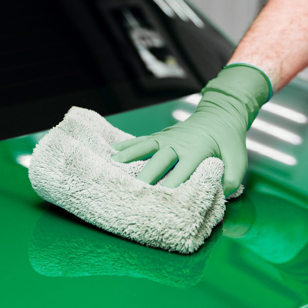 Hand mit Mikrofasertuch bei der Reinigung einer Fahrzeugoberfläche in Steyr