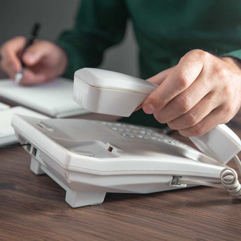 Hand nimmt Telefonhörer für Kontaktaufnahme in der Werkstatt in Steyr